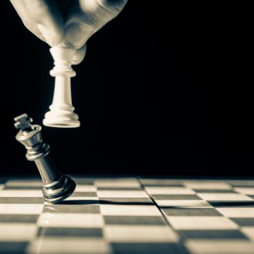 اليد تمسك بالملك الأبيض وتنزل الملك الأسود على لوحة الشطرنج.